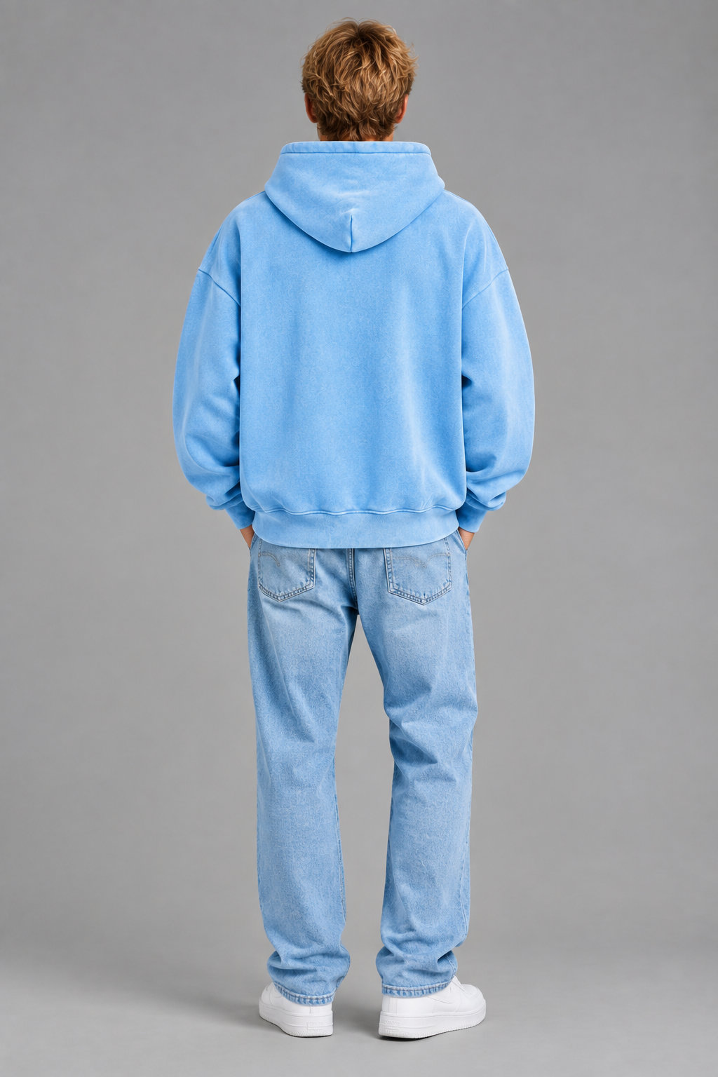 Full-body back view of the blonde model wearing the hoodie